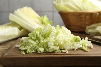 Photo of Cut Chinese cabbages and knife on wooden table, closeup
