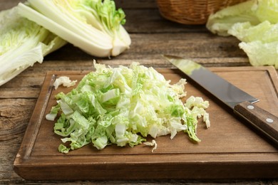 Photo of Cut Chinese cabbages and knife on wooden table, closeup