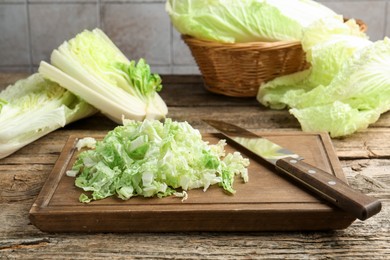 Photo of Cut Chinese cabbages and knife on wooden table, closeup