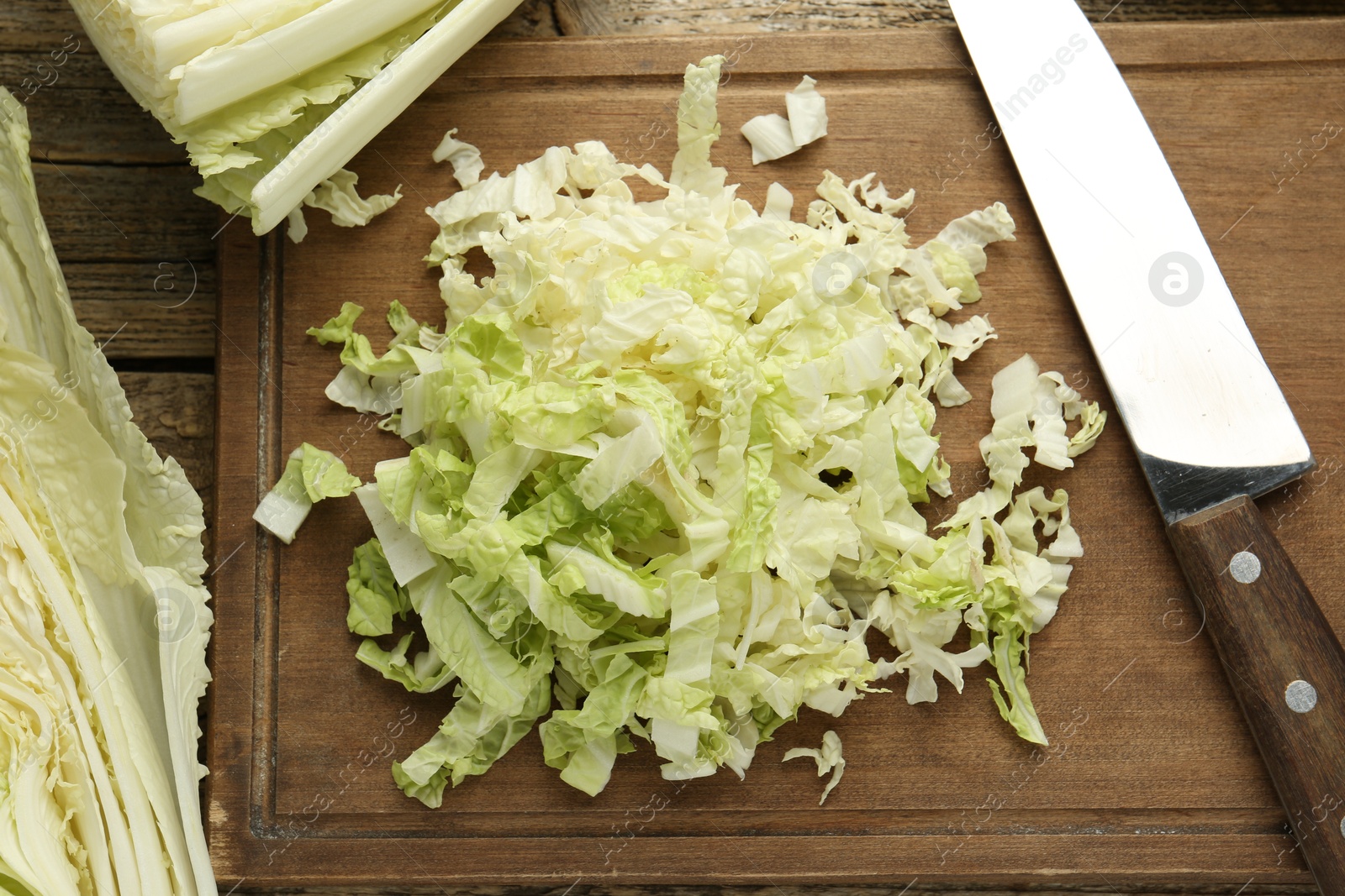 Cut Chinese cabbages and knife on wooden table, flat lay Photo of Cut Chinese cabbages and knife on wooden table, flat lay
