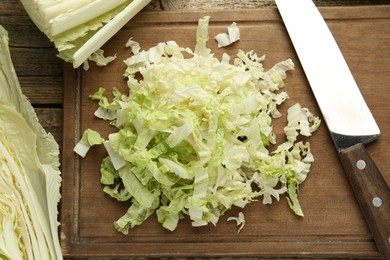Photo of Cut Chinese cabbages and knife on wooden table, flat lay
