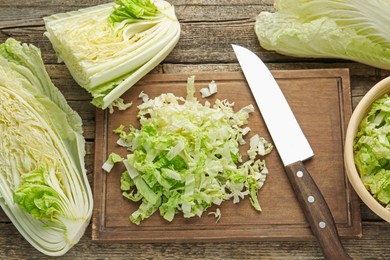Photo of Cut Chinese cabbages and knife on wooden table, flat lay