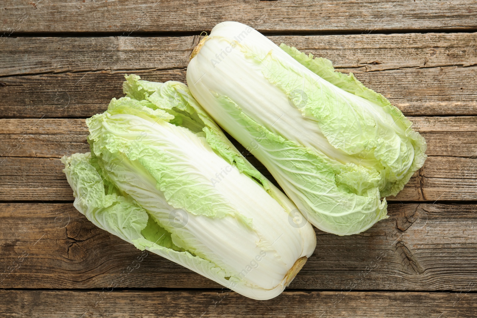 Photo of Fresh Chinese cabbages on wooden table, top view