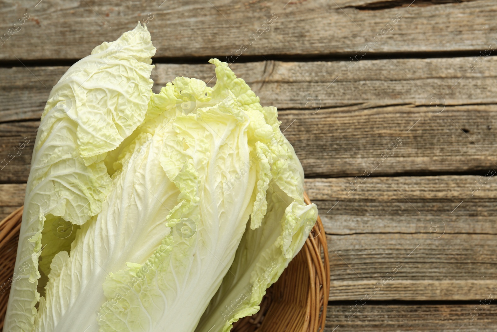 Fresh Chinese cabbage in wicker basket on wooden table, top view. Space for text Photo of Fresh Chinese cabbage in wicker basket on wooden table, top view. Space for text