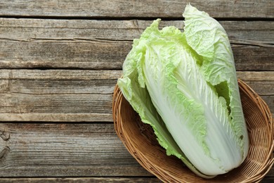 Photo of Fresh Chinese cabbage in wicker basket on wooden table, top view. Space for text