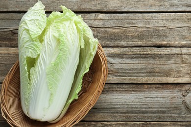 Photo of Fresh Chinese cabbage in wicker basket on wooden table, top view. Space for text
