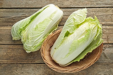 Photo of Fresh Chinese cabbages in wicker basket on wooden table, top view