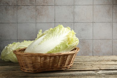 Photo of Fresh Chinese cabbages in wicker basket on wooden table, closeup. Space for text