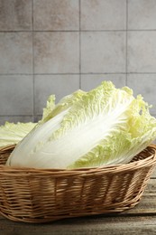 Photo of Fresh Chinese cabbages in wicker basket on wooden table, closeup
