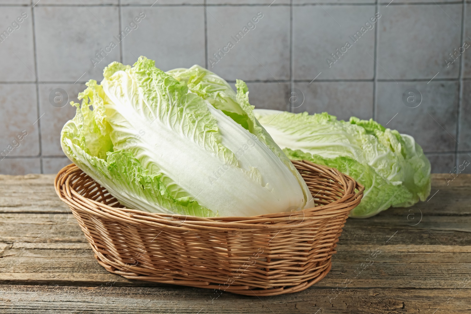 Fresh Chinese cabbages in wicker basket on wooden table, closeup Photo of Fresh Chinese cabbages in wicker basket on wooden table, closeup