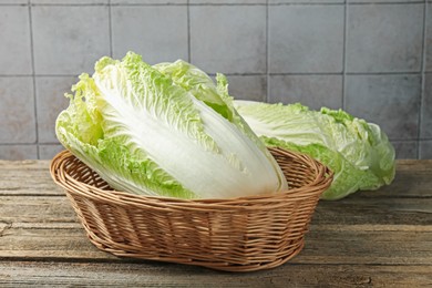 Photo of Fresh Chinese cabbages in wicker basket on wooden table, closeup