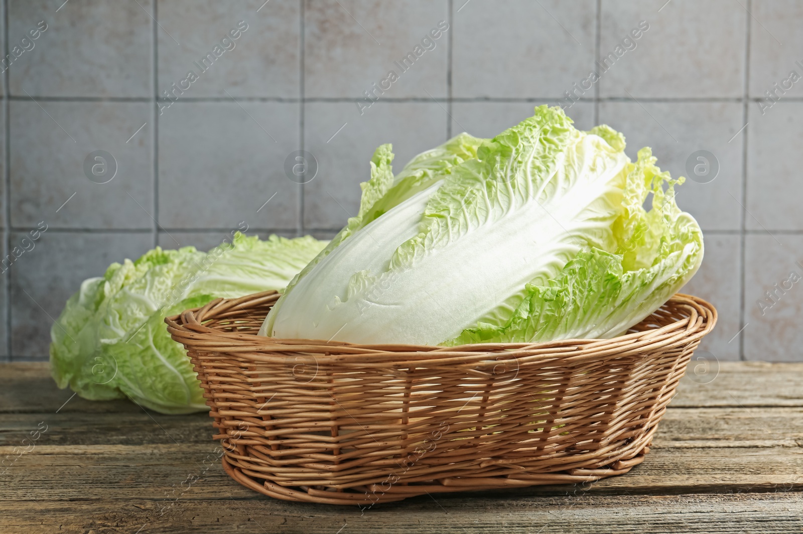Fresh Chinese cabbages in wicker basket on wooden table, closeup Photo of Fresh Chinese cabbages in wicker basket on wooden table, closeup