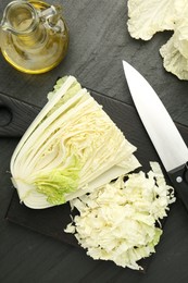 Photo of Cut Chinese cabbage and knife on black table, flat lay