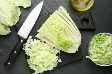 Photo of Cut Chinese cabbage and knife on black table, flat lay
