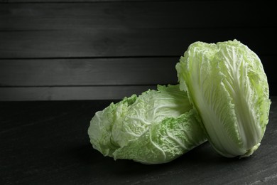 Photo of Fresh Chinese cabbages on black table, closeup. Space for text