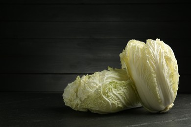Photo of Fresh Chinese cabbages on black table, closeup. Space for text