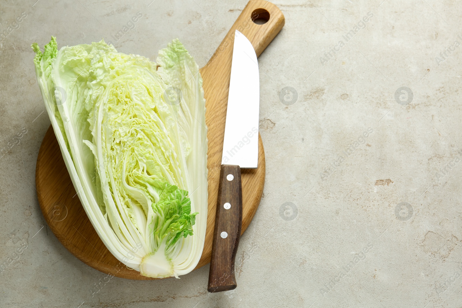 Cut Chinese cabbage and knife on light grey table, top view. Space for text Photo of Cut Chinese cabbage and knife on light grey table, top view. Space for text