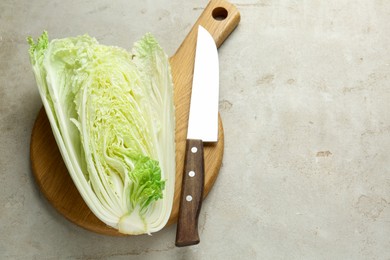 Photo of Cut Chinese cabbage and knife on light grey table, top view. Space for text