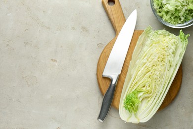 Photo of Cut Chinese cabbage and knife on light grey table, top view. Space for text