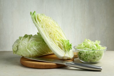 Photo of Fresh Chinese cabbages and knife on light grey table, closeup