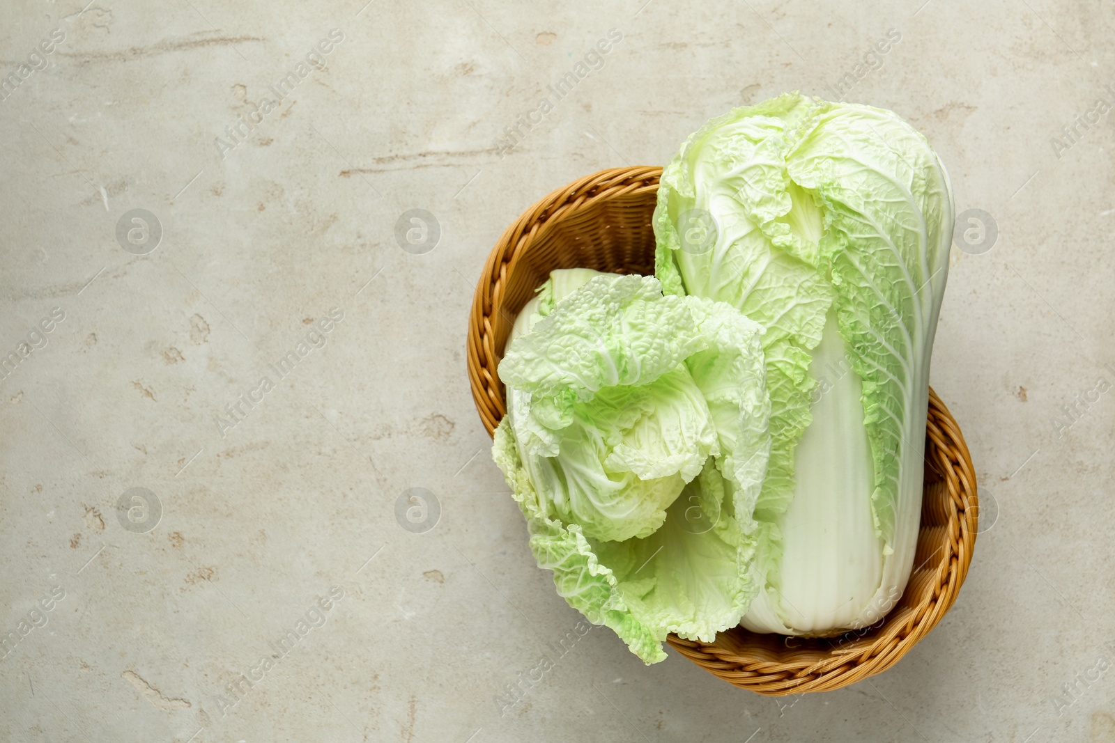 Fresh Chinese cabbages in wicker basket on light grey table, top view. Space for text Photo of Fresh Chinese cabbages in wicker basket on light grey table, top view. Space for text