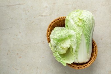 Photo of Fresh Chinese cabbages in wicker basket on light grey table, top view. Space for text