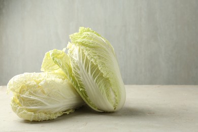 Photo of Fresh Chinese cabbages on light grey table, closeup. Space for text