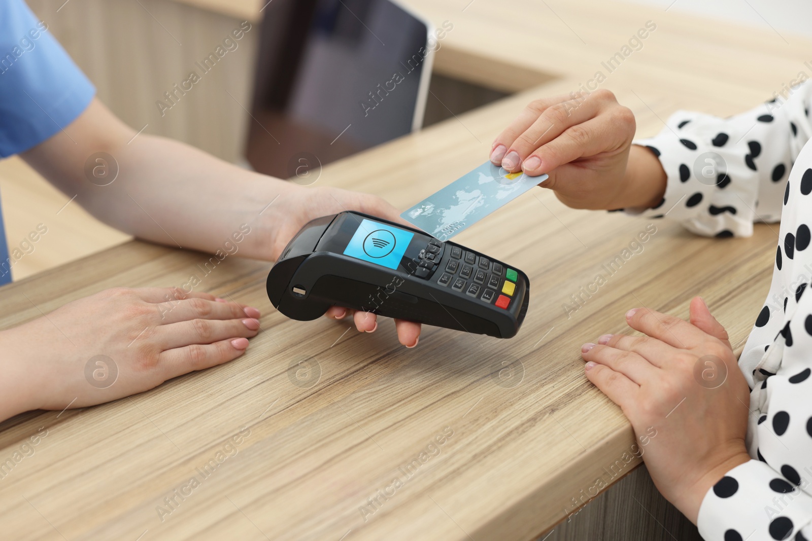 Receptionist taking payment from client via terminal at hospital, closeup Image of Receptionist taking payment from client via terminal at hospital, closeup