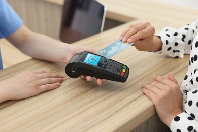 Image of Receptionist taking payment from client via terminal at hospital, closeup