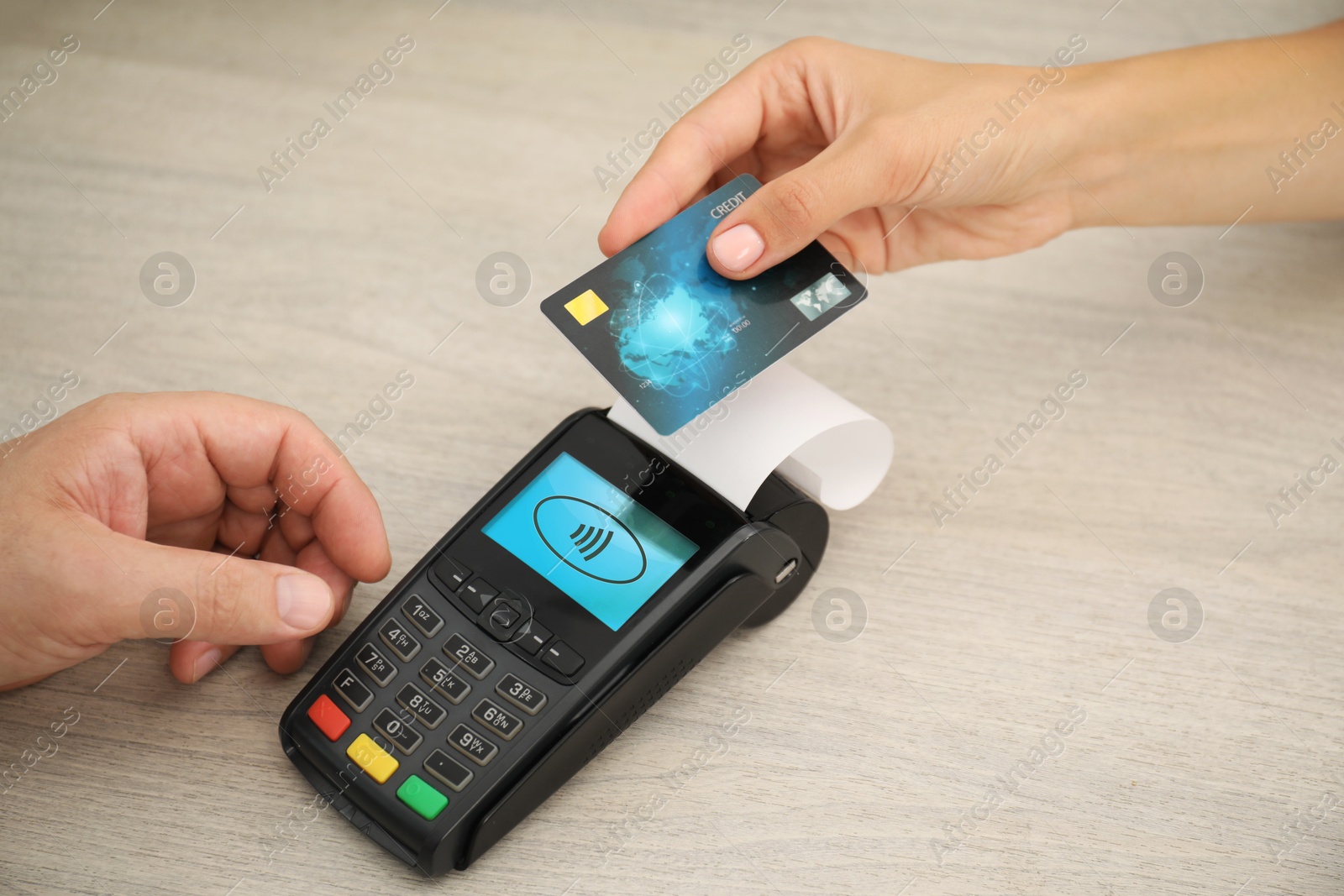 Man taking payment from client via terminal at wooden table, closeup Image of Man taking payment from client via terminal at wooden table, closeup