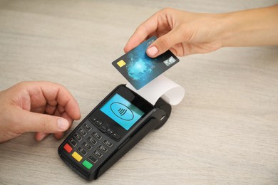 Image of Man taking payment from client via terminal at wooden table, closeup