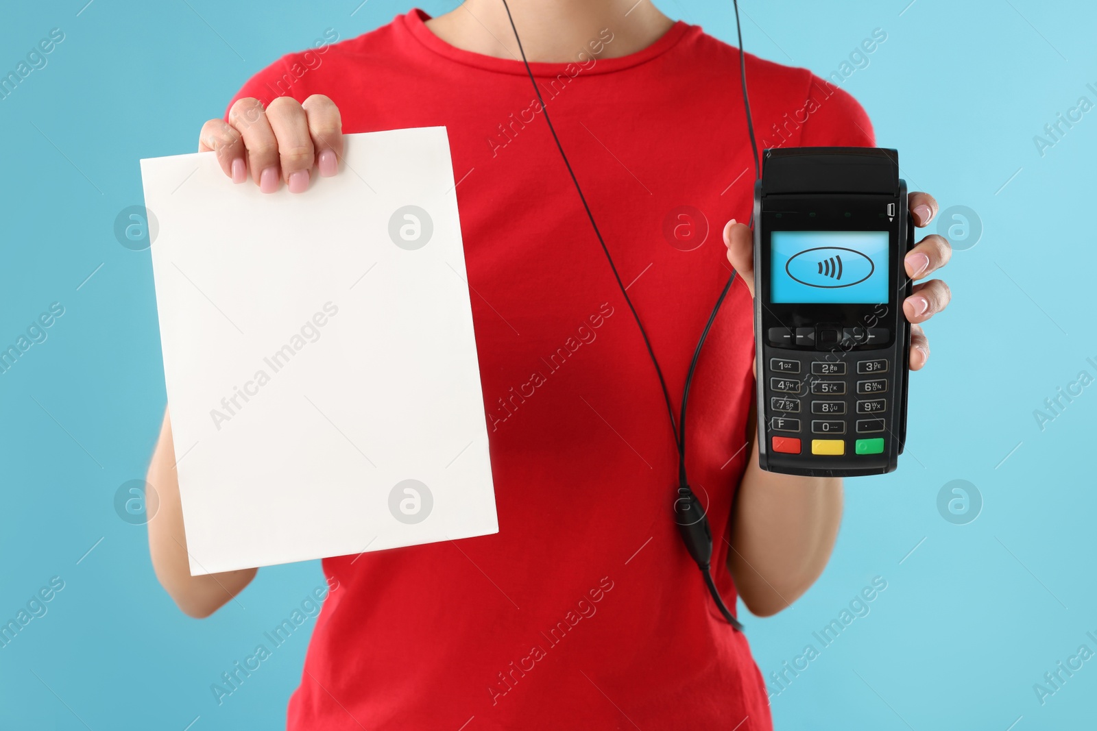 Worker holding payment terminal and paper on light blue background, closeup Image of Worker holding payment terminal and paper on light blue background, closeup