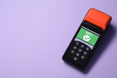 Image of Payment terminal with NFC system on pale purple background, top view. Space for text