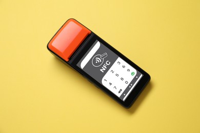 Image of Payment terminal with NFC system on pale orange background, top view