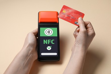 Image of Woman paying with credit card via terminal on dark beige background, closeup