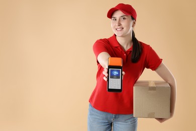 Image of Worker holding payment terminal with NFC system and cardboard box on pale brown background. Space for text