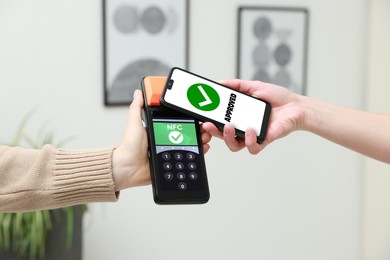 Image of Payment terminal with NFC system. Client using mobile phone to pay for service indoors, closeup