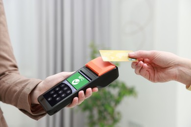 Image of Payment terminal with NFC system. Client using credit card to pay for service indoors, closeup