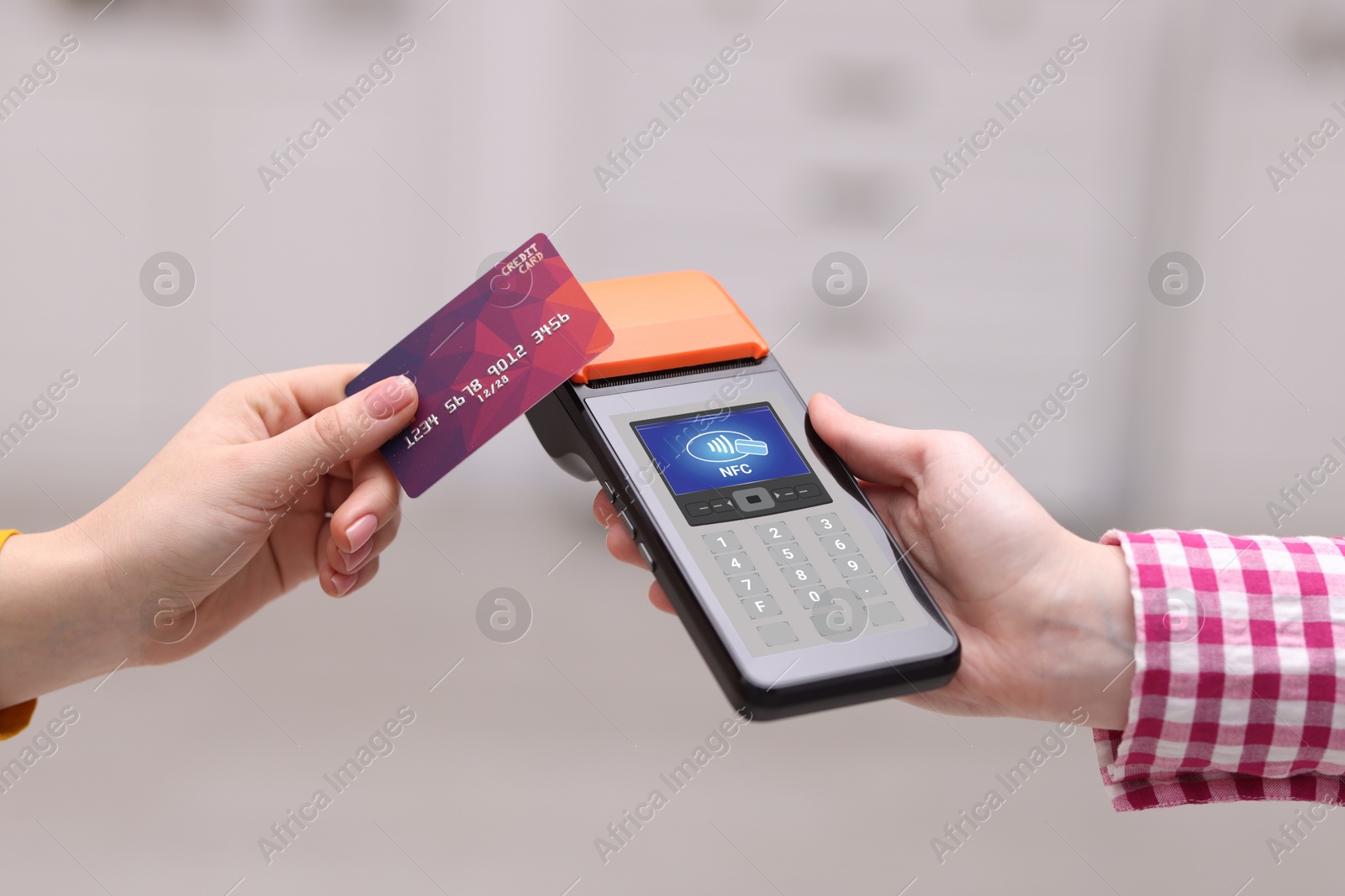 Payment terminal with NFC system. Client using credit card to pay for service indoors, closeup Image of Payment terminal with NFC system. Client using credit card to pay for service indoors, closeup