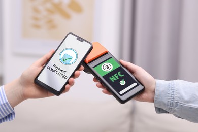 Image of Payment terminal with NFC system. Client using mobile phone to pay for service indoors, closeup
