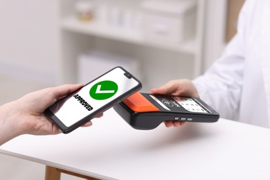 Image of Payment terminal with NFC system. Client using mobile phone to pay for service in hospital, closeup