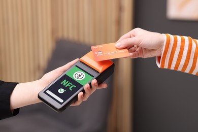 Image of Payment terminal with NFC system. Client using credit card to pay for service indoors, closeup