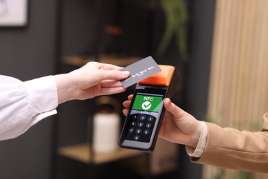 Image of Payment terminal with NFC system. Client using credit card to pay for service indoors, closeup