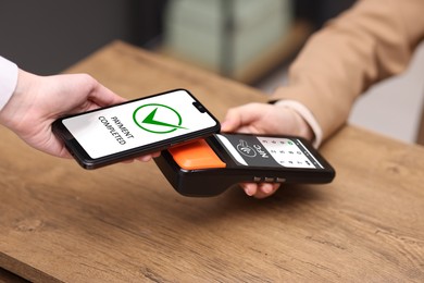 Image of Payment terminal with NFC system. Client using mobile phone to pay for service indoors, closeup