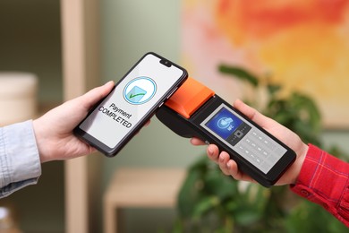 Image of Payment terminal with NFC system. Client using mobile phone to pay for service indoors, closeup