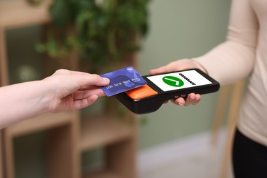 Image of Payment terminal with NFC system. Client using credit card to pay for service indoors, closeup