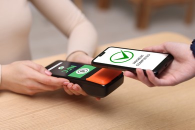 Image of Payment terminal with NFC system. Client using mobile phone to pay for service indoors, closeup