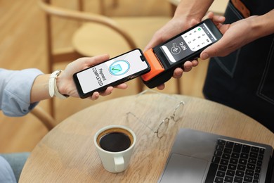Image of Payment terminal with NFC system. Client using mobile phone to pay for service in cafe, closeup
