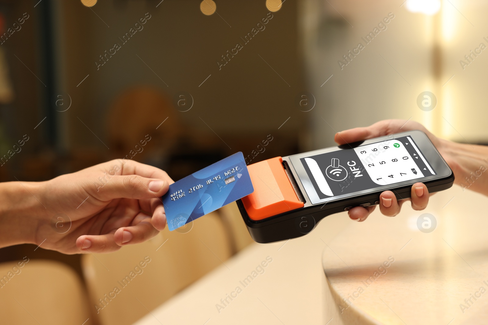 Payment terminal with NFC system. Client using credit card to pay for service indoors, closeup Image of Payment terminal with NFC system. Client using credit card to pay for service indoors, closeup