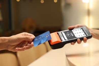 Image of Payment terminal with NFC system. Client using credit card to pay for service indoors, closeup
